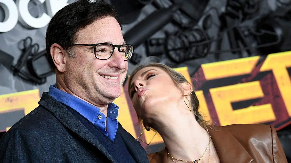 Kelly Rizzo leaning in to kiss Bob Saget.