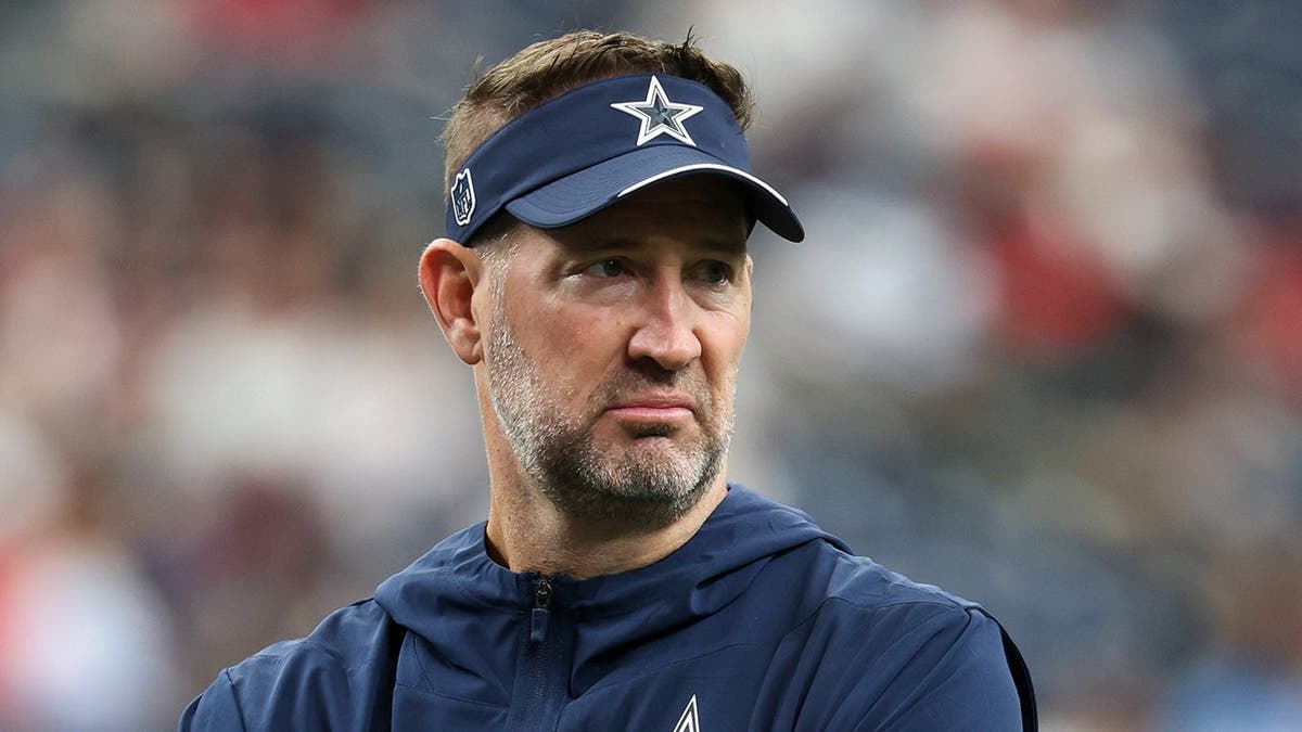 Brian Schottenheimer stands on the field during warmups in Houston.