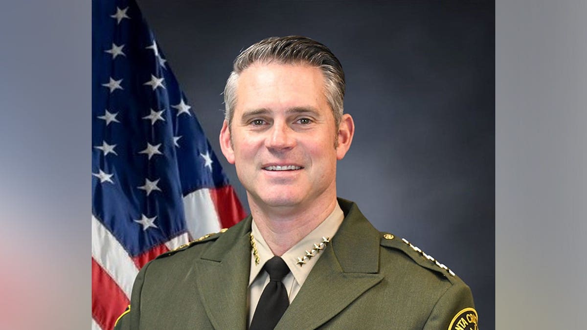 Santa Cruz County Sheriff Chris Clark poses in uniform in front of an American flag.