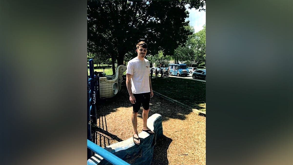 Missing Maryland man Phoenix Phillips stands outdoors near playground equipment.