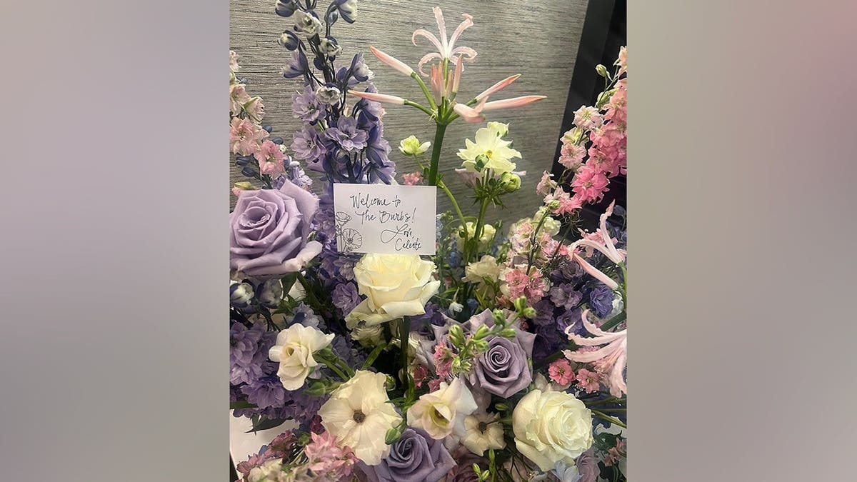 A bouquet of pink and purple flowers sits beside a handwritten welcome note for Elizabeth Hurley on the set of 