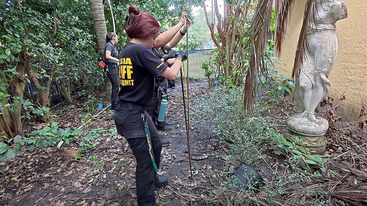 Volusia County investigators search a wooded area beside a home in DeBary, Florida.