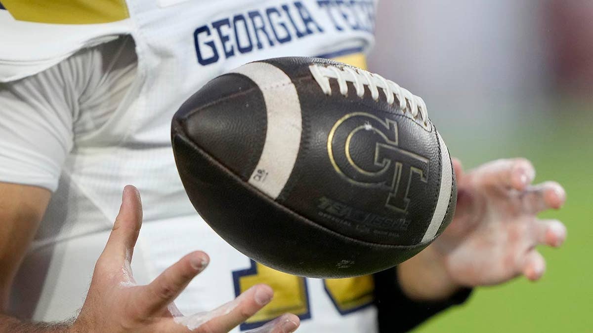 A Georgia Tech football player holding a football during warmups