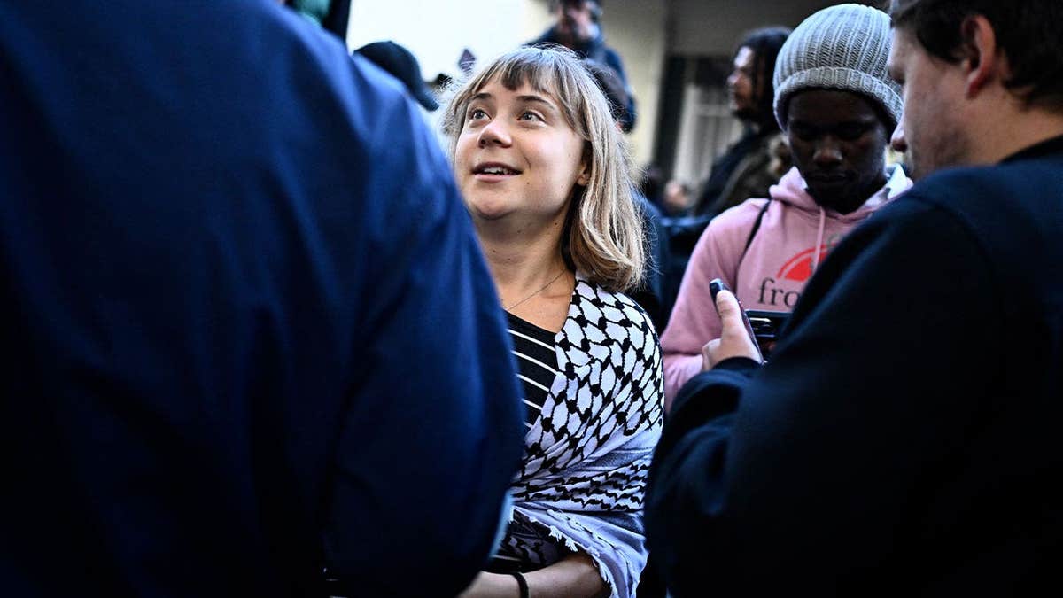 Greta Thunberg talks with a group of people while wearing a black-and-white scarf in France
