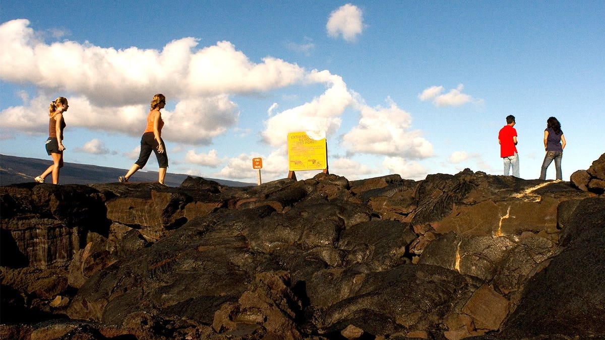 Tourists walking along cliff at Hawaii Volcanos National Park