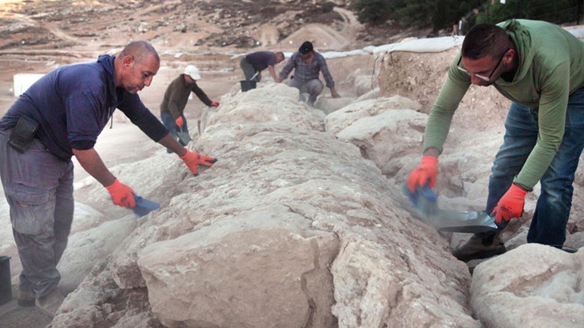 Archaeologists analyzing ancient aqueduct