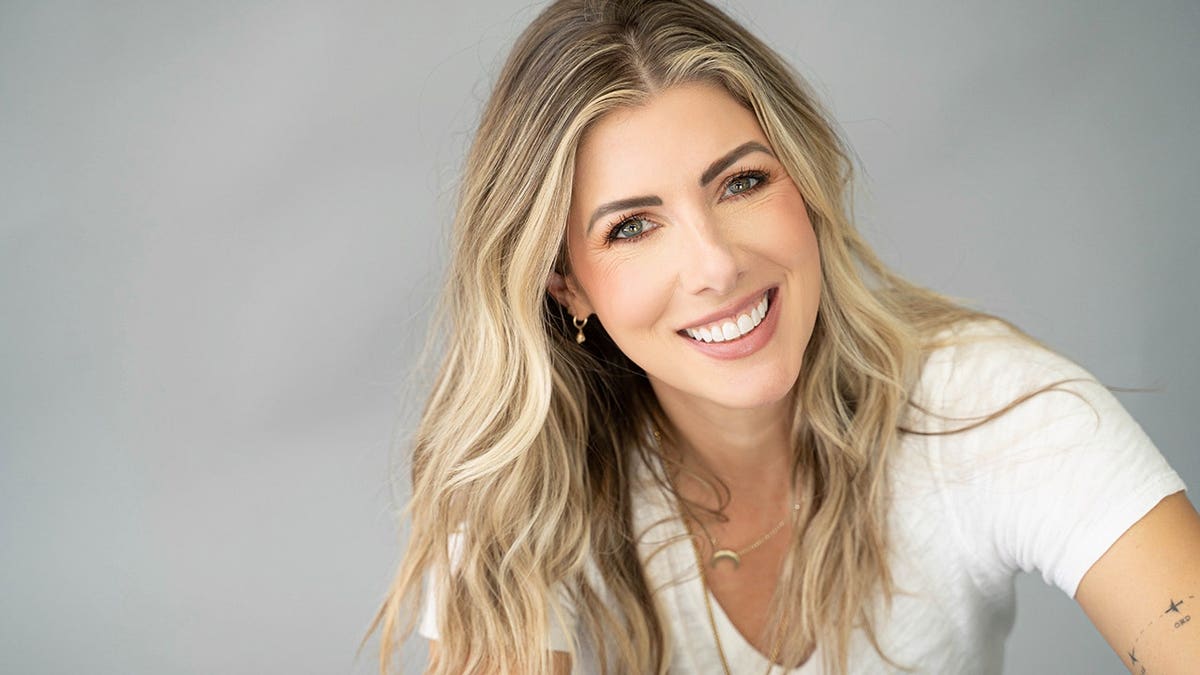 Kelly Rizzo smiling in a white shirt.