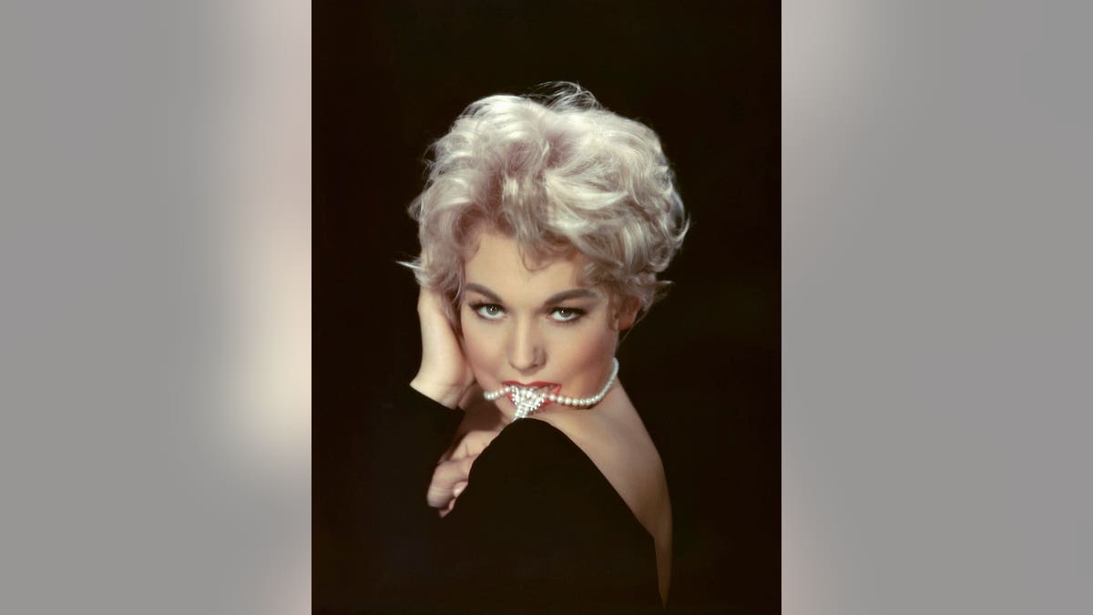 Kim Novak bites a pearl necklace in a publicity portrait from the 1950s.