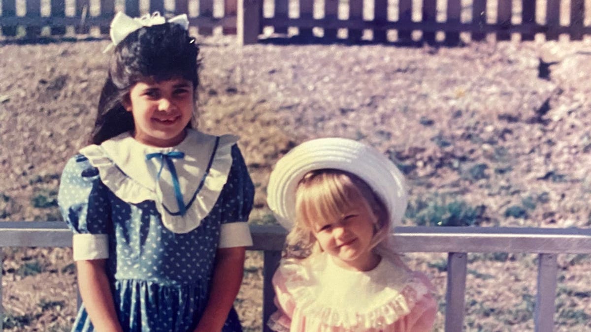Lauren Burns and Miranda Lambert as children dressed up in formal wear and smiling.