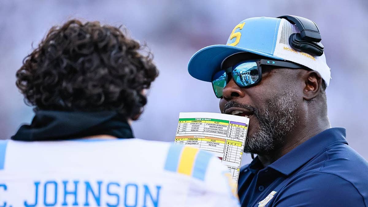 Marshall Faulk coaches a quarterback during a college football game
