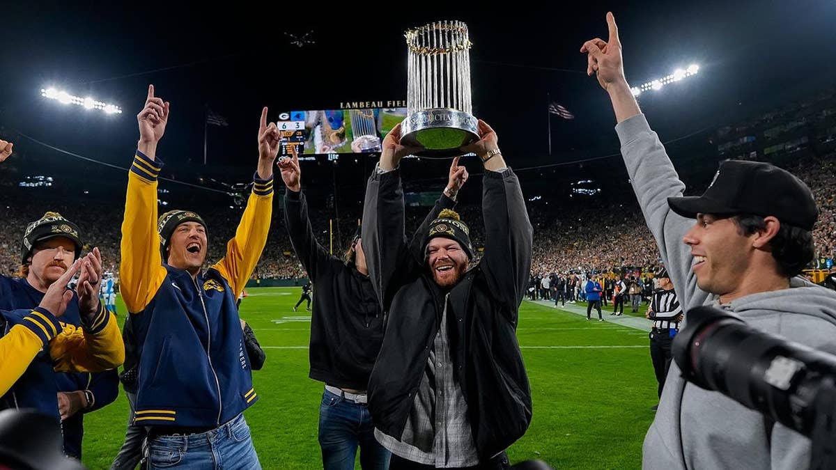 Brewers players celebrate with the Commissioner's Trophy at Lambeau Field