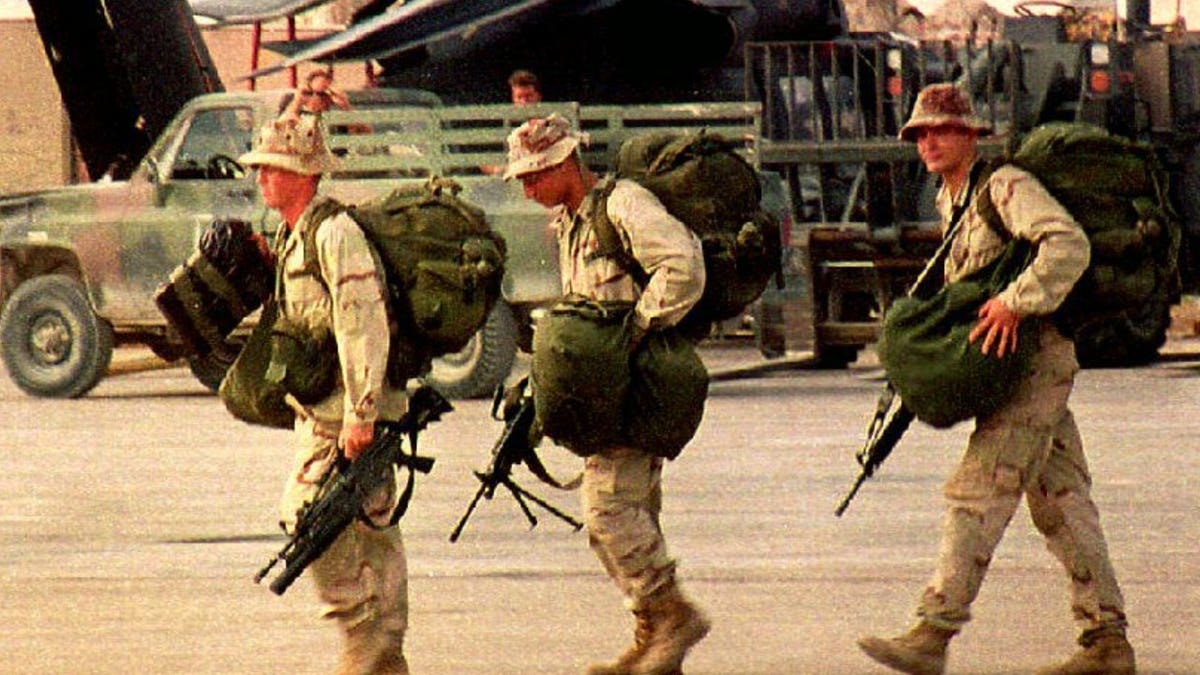 Homeward bound U.S. Army Rangers carry their bags and M-16 rifles toward a military transport plane at Mogadishu International airport.