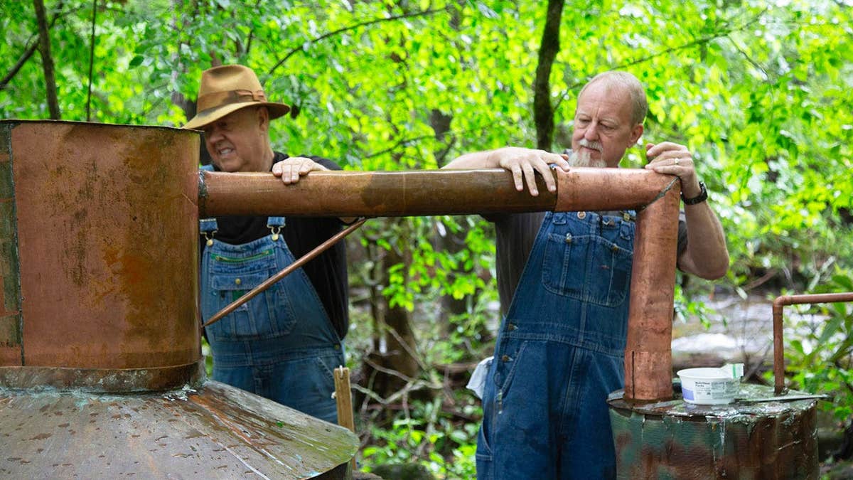 Mark Ramsey and Digger Manes making moonshine outdoors.