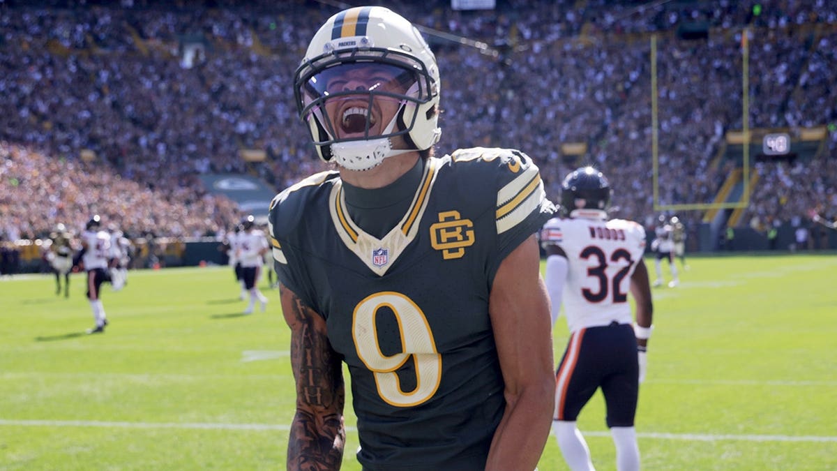 Christian Watson celebrates after catching a touchdown pass during an NFL game.