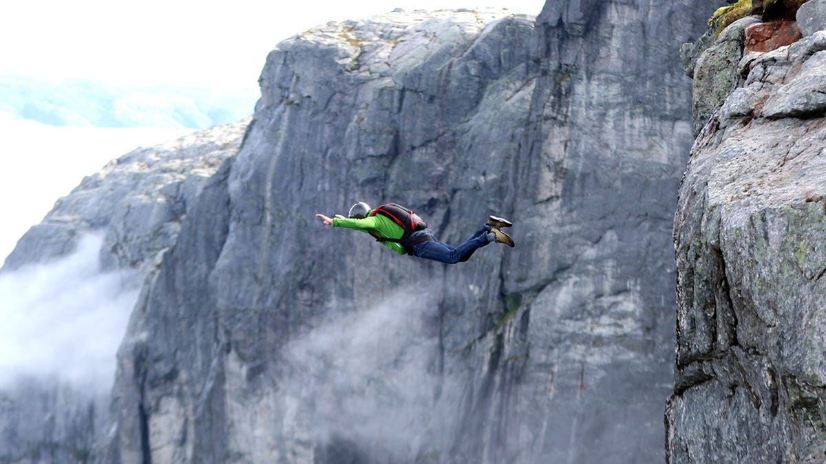 BASE jumper jumping off cliff