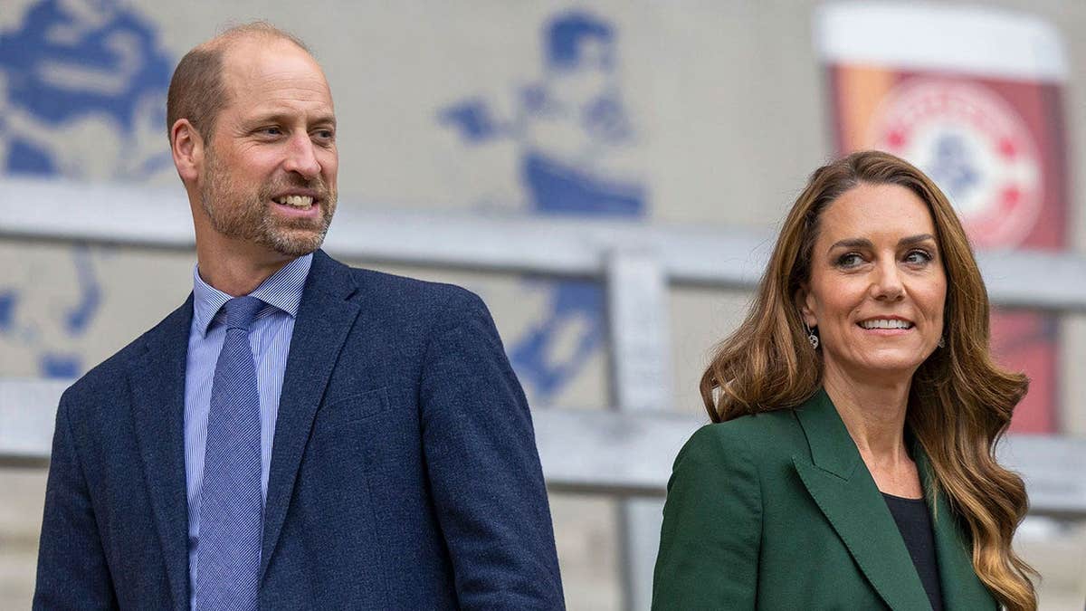 Prince William and Kate Middleton with their backs turned outside a stadium.