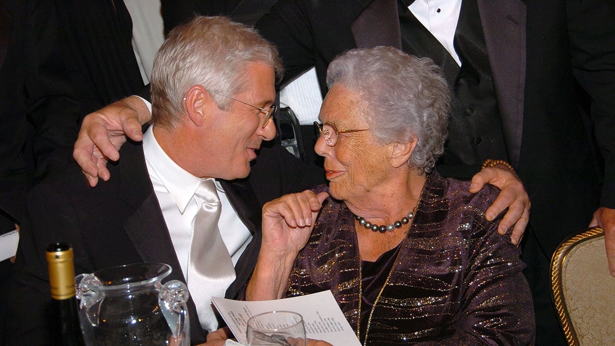 Richard Gere and Doris Gere stand together at an indoor benefit event.