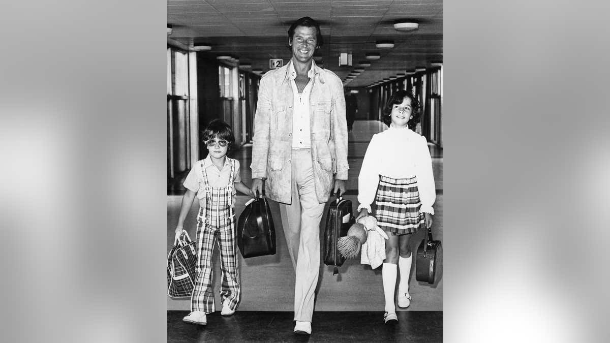Roger Moore walks through London Airport with his son Geoffrey, age six, and daughter Deborah, age eight.