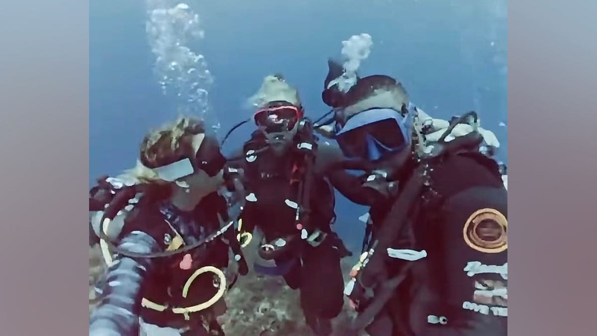 Amy Schumer wears scuba diving gear while exploring underwater.