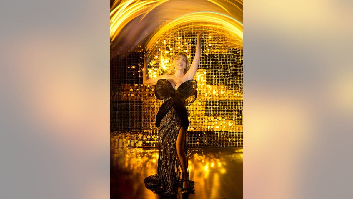 Taylor Dayne in a bow black dress against a golden backdrop.