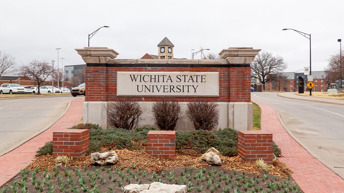 A brick and stone Wichita State University entrance sign stands along a campus roadway in Wichita, Kansas.