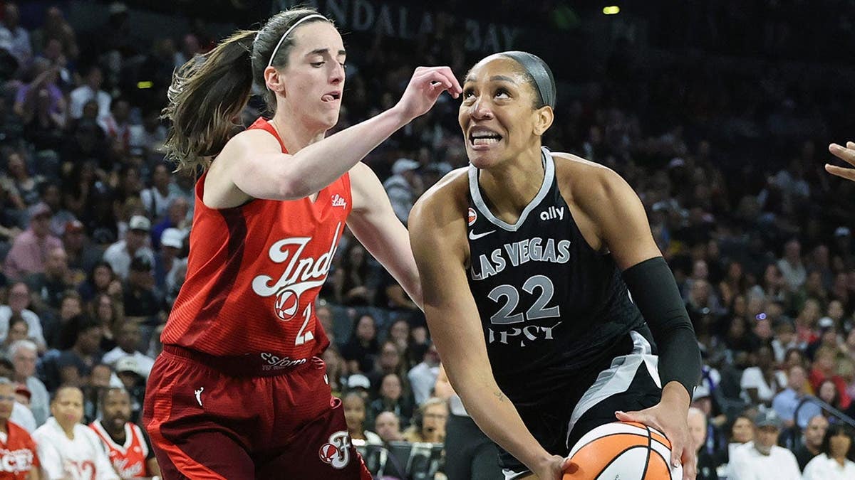 A'ja Wilson of the Las Vegas Aces drives to the basket against Caitlin Clark of the Indiana Fever.