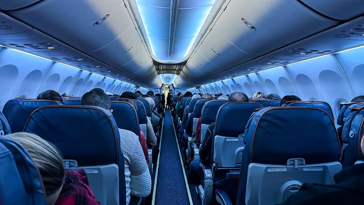 People sit inside an airplane cabin.