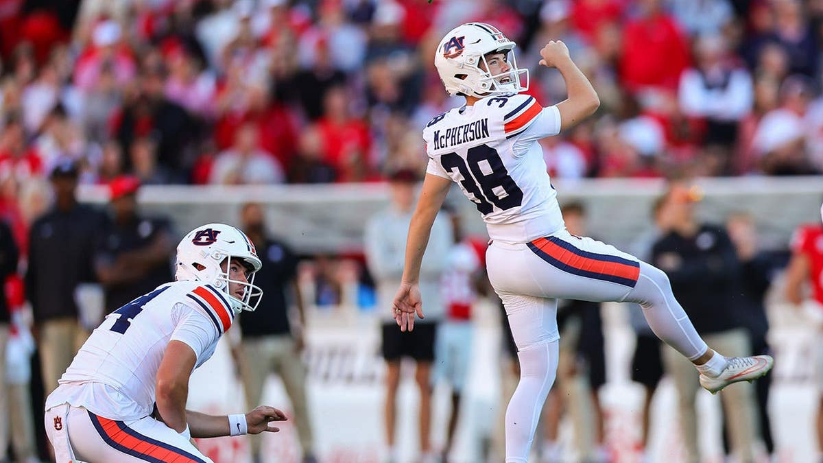Auburn kicker Alex McPherson kicks a field goal as holder Hudson Kaak looks on during an NCAA college football game.