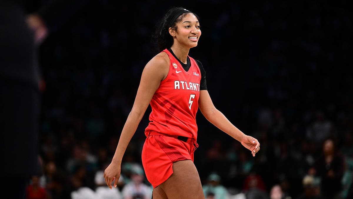 Angel Reese smiles during a WNBA semifinal game against the New York Liberty.