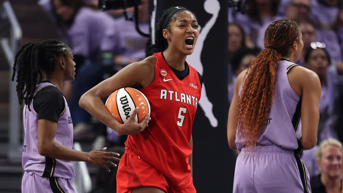 Angel Reese #5 reacts between Tiffany Hayes and Kiah Stokes during WNBA Finals game two.
