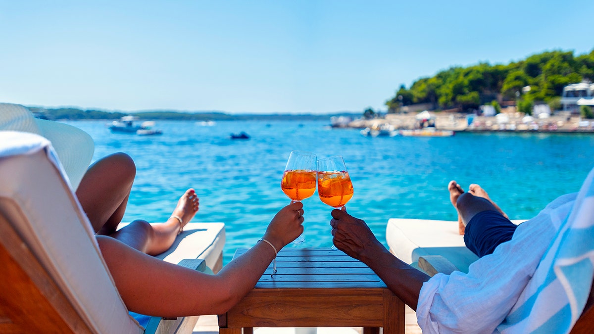 A man and a woman drink an aperitif on the beach.