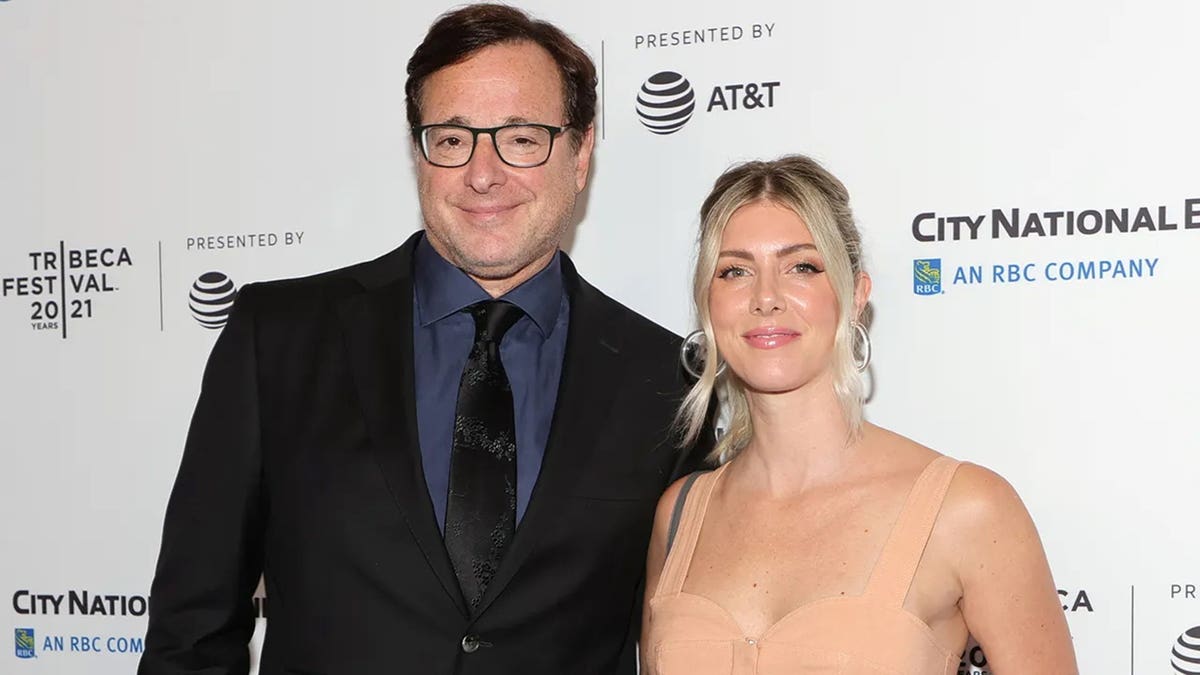 Bob Saget and Kelly Rizzo smiling together at a movie premiere.
