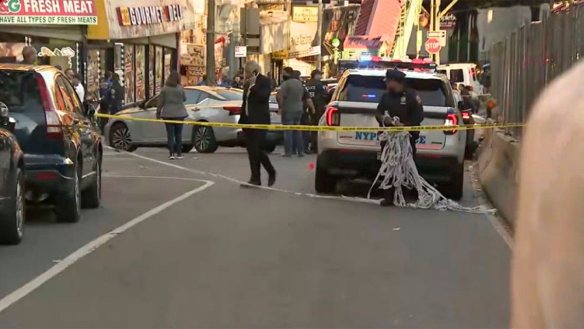 NYPD officers and police vehicles behind yellow crime scene tape following a shooting in the Bronx