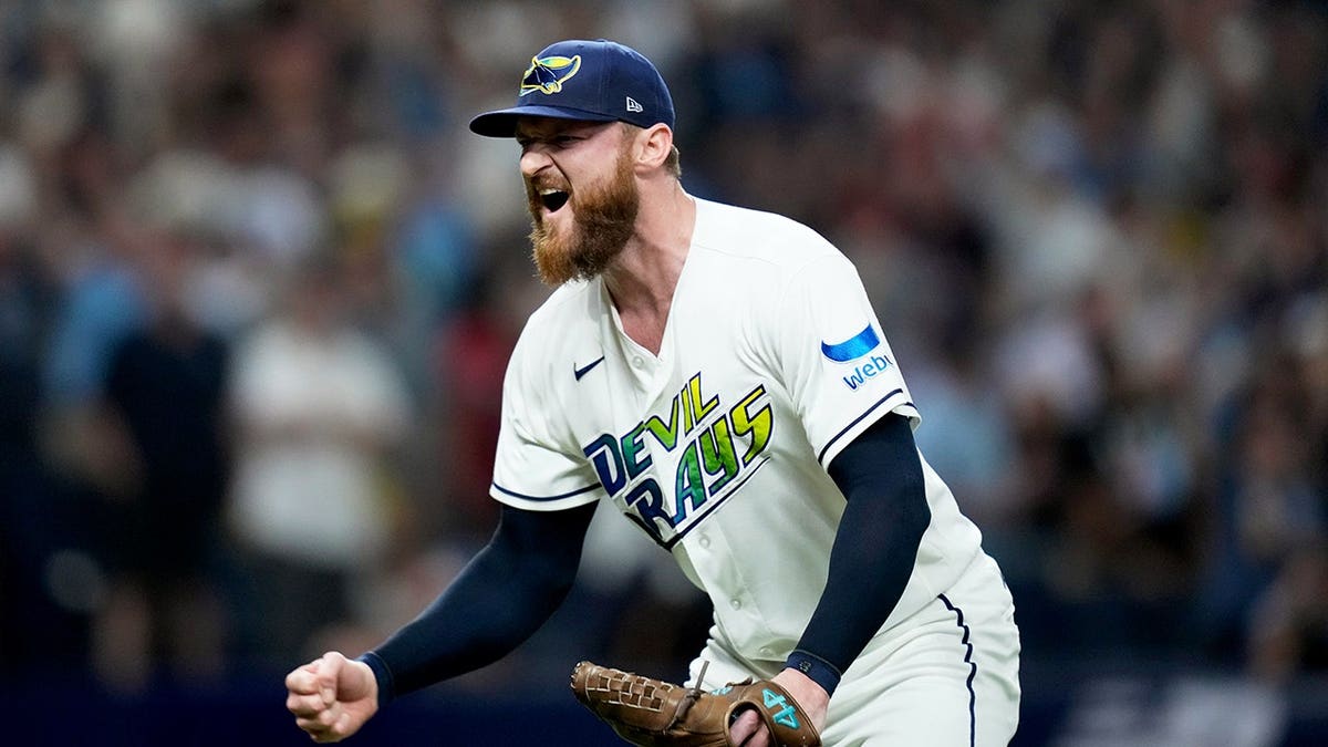Bryan Baker celebrates on the field after the Rays beat the Guardians.