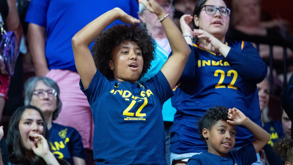 Fans wearing Caitlin Clark shirts wave during a t-shirt toss at Mohegan Sun Arena.