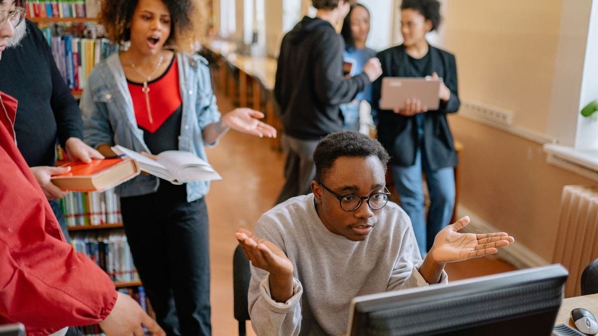 Confused students gathered around a computer