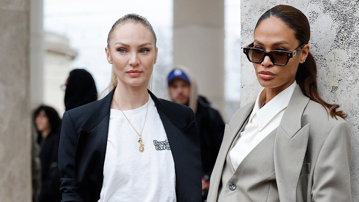 Candice Swanepoel and Joan Smalls stand outside Elie Saab during Paris Fashion Week.
