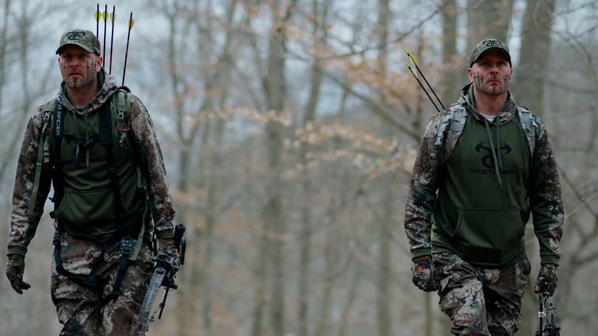 Chad and James Hampton dressed in camouflage and holding bows and arrows.