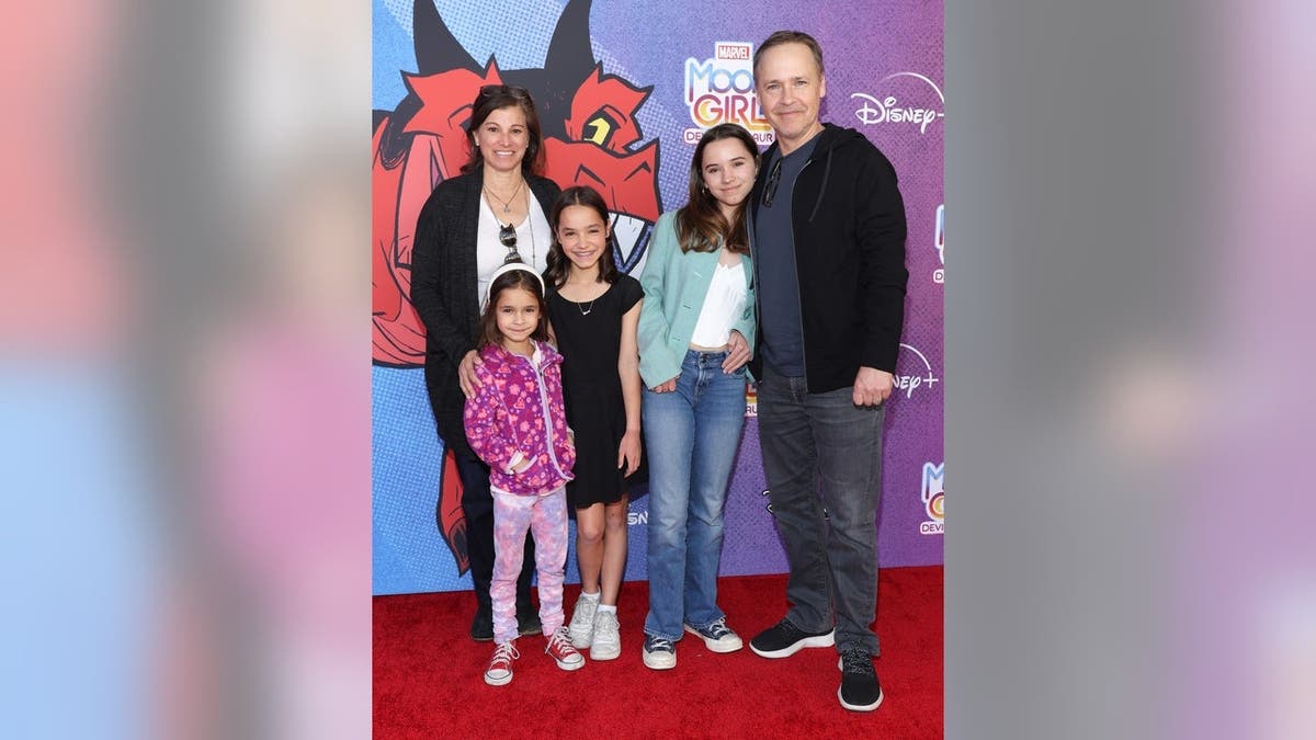 Chad Lowe, Kim Painter, and three children stand together on a red carpet at a premiere event.