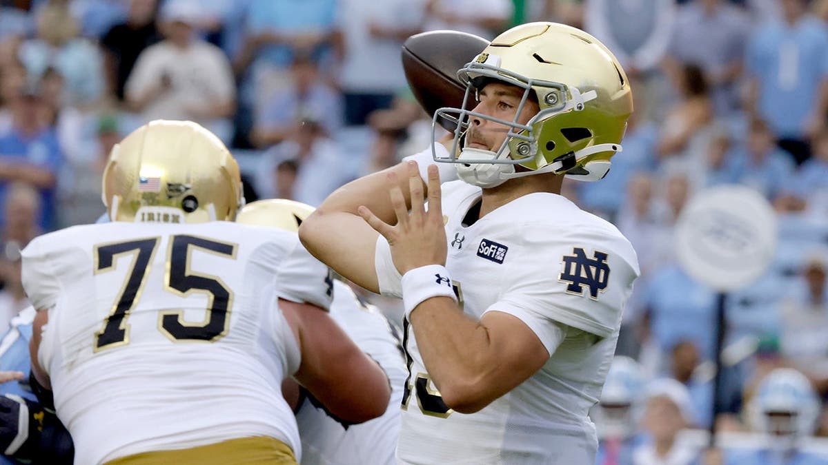 CJ Carr looks to pass against North Carolina behind offensive lineman Sullivan Absher during a college football game.