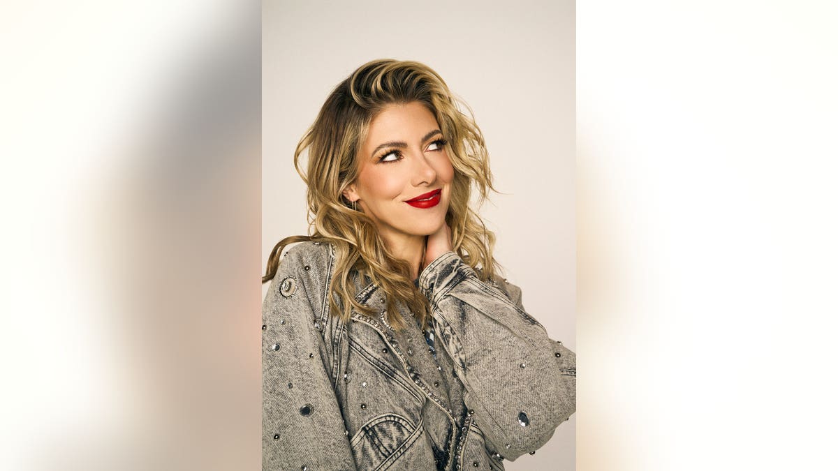 Kelly Rizzo stands in a studio setting.