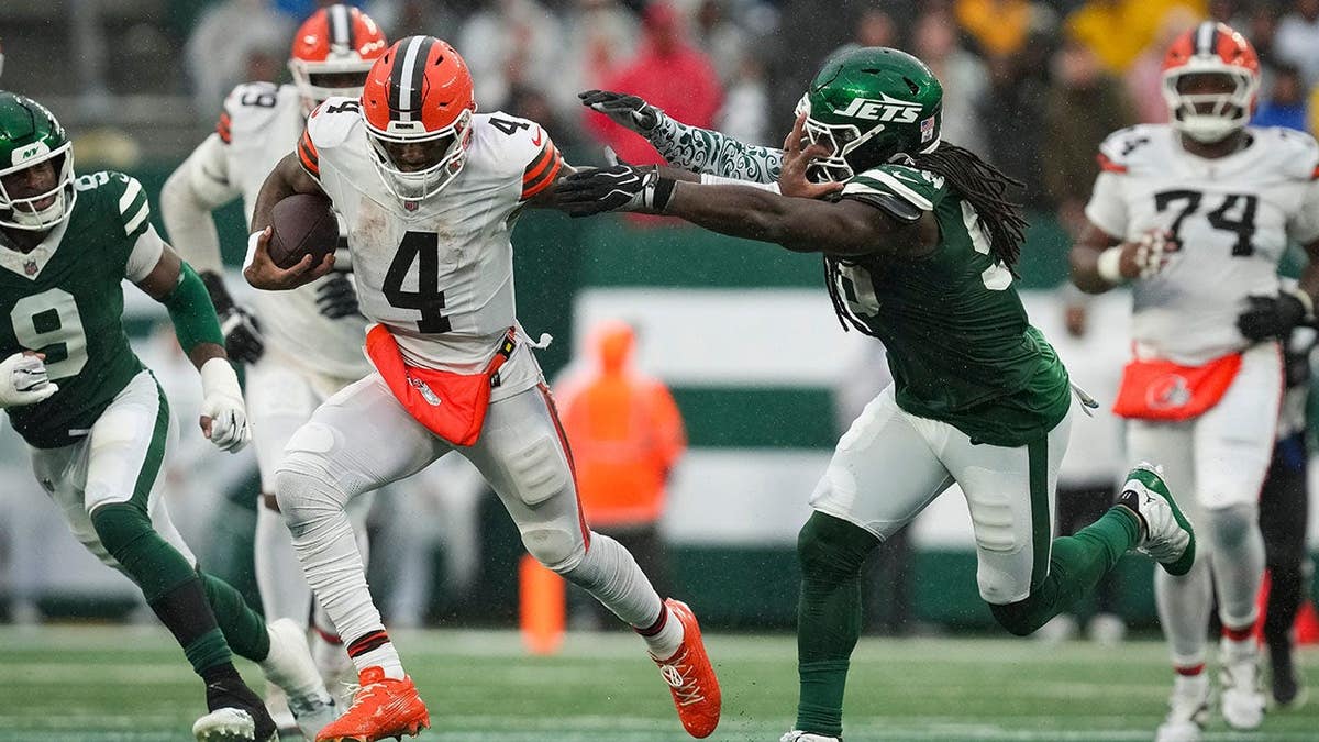 Deshaun Watson runs with the ball as Demario Davis defends during a game.