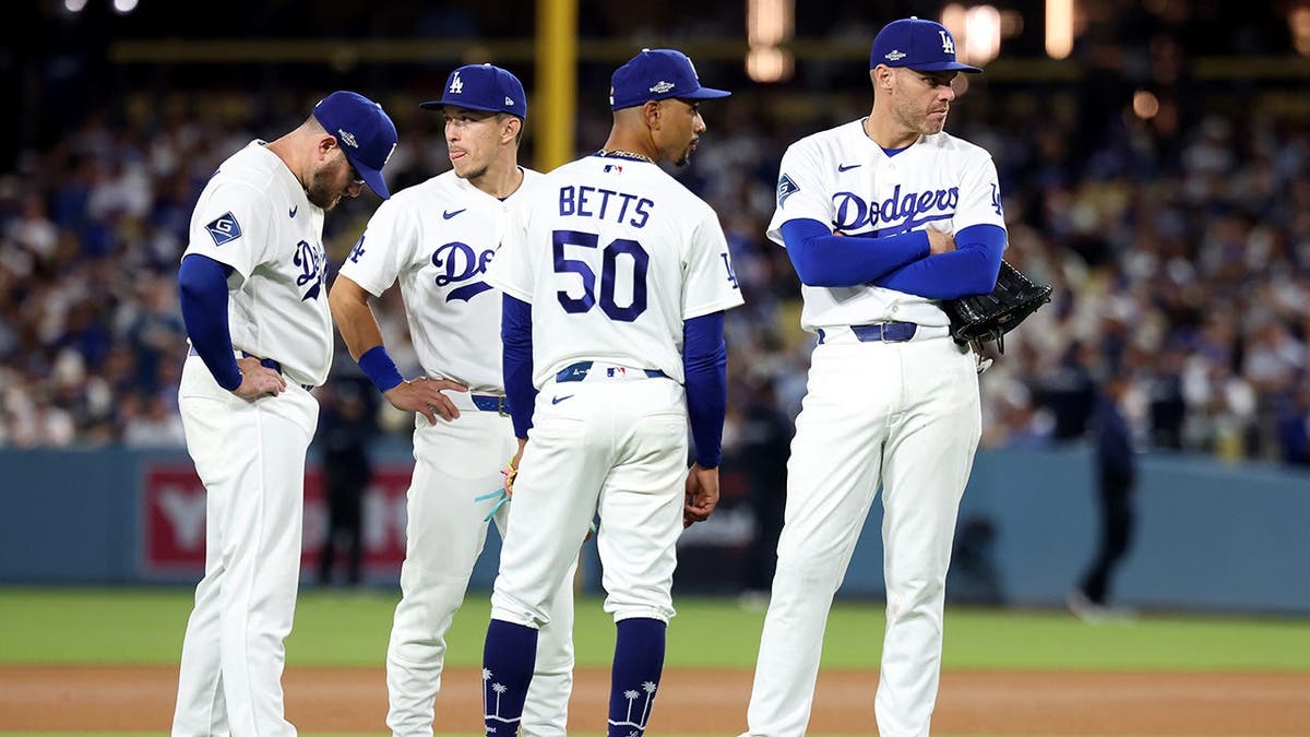 Max Muncy, Tommy Edman, Mookie Betts and Freddie Freeman of the Los Angeles Dodgers look on during a pitching change.