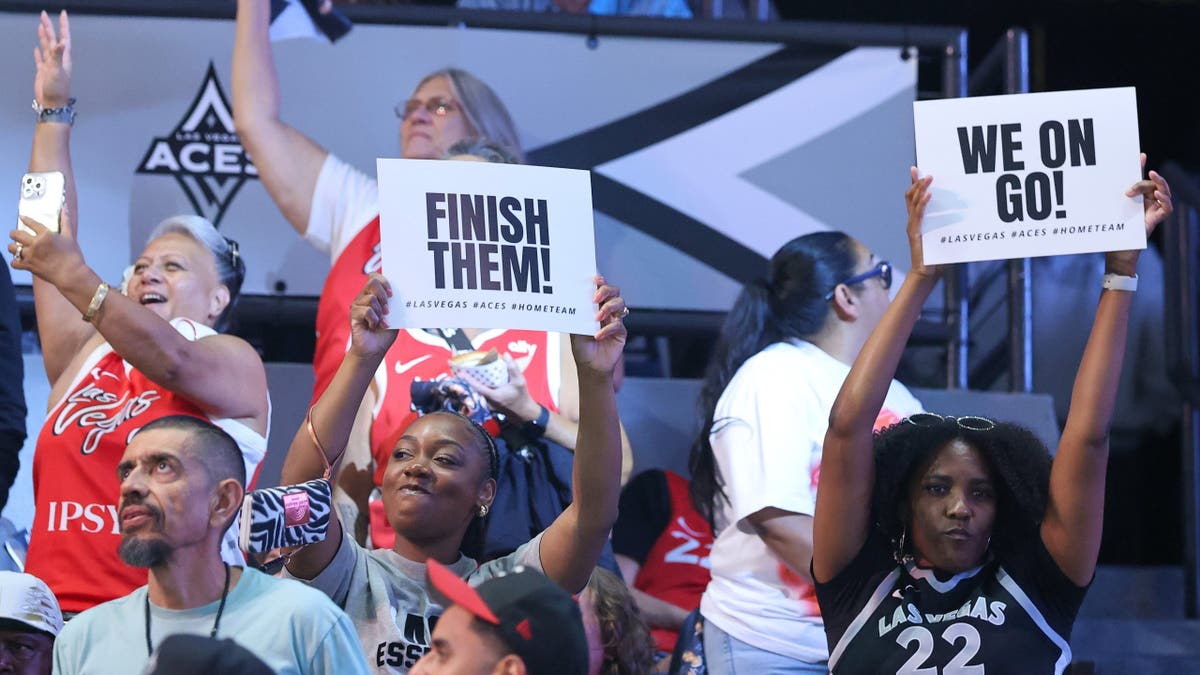 Fans hold up signs at Michelob ULTRA Arena during a WNBA playoff game.
