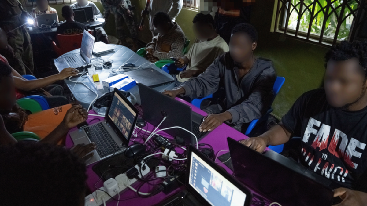 People seated at tables using laptop computers inside a suspected scam center in Ghana