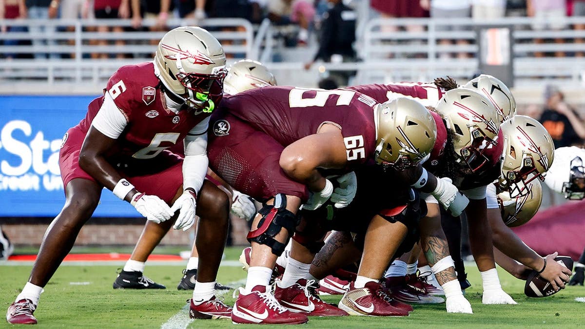 Florida State Seminoles and New Mexico State Aggies line up at the line of scrimmage during a football game.