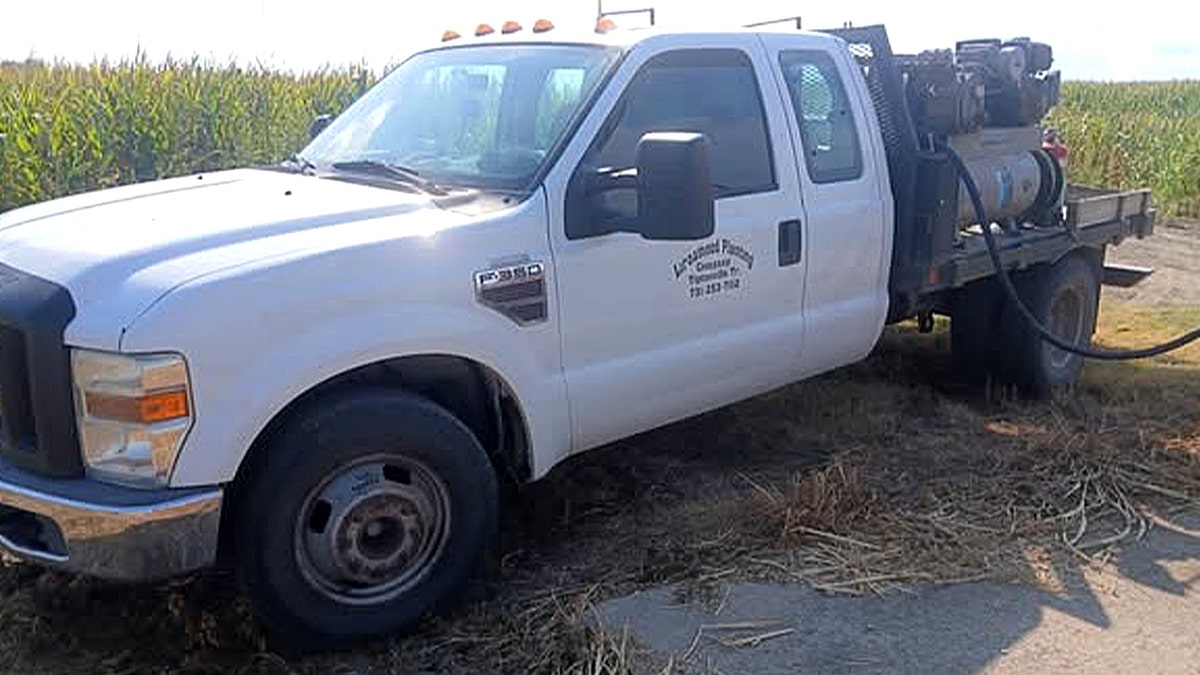 White heavy-duty pickup truck with an air compressor in the bed.