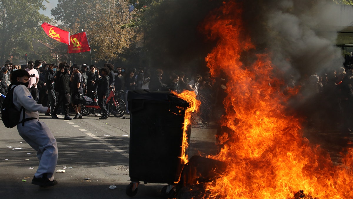 Manifestantes junto a un contenedor de basura en llamas en Francia