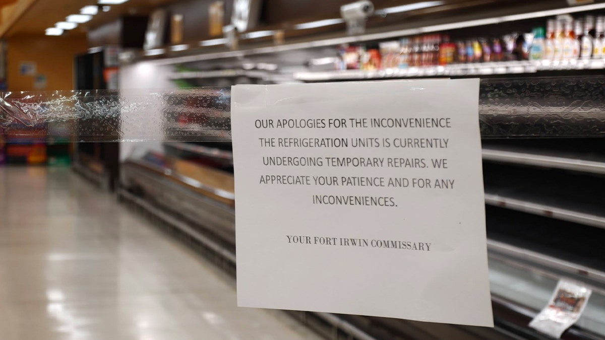 sign posted in front of empty fridge section