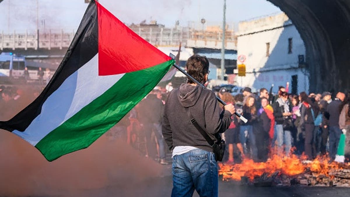 A fire burns as people gather to support the Global Sumud Flotilla at the Port of Genoa on Oct. 3, 2025, in anti-Israel protests in Genoa, Italy. The Commission for the Guarantee declares the strike illegitimate for lack of proper notice, but dockworkers, students and civil society activists join the protests.